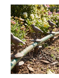 Rustic cast iron bird garden hose guide stake preventing damage to lawn and flowers