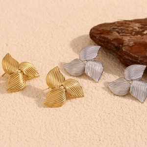 Three-leaf clover stud earrings in gold and silver with brushed metal finish texture