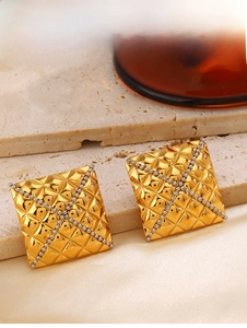 Close-up of golden square stud earrings with quilted pattern and silver bead accents