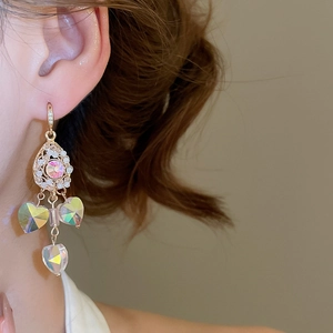 Close-up of vintage gold hollow filigree earrings with pearl and heart crystal tassels