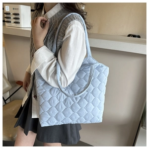 Close-up of light blue quilted tote bag with diamond pattern and soft shoulder straps