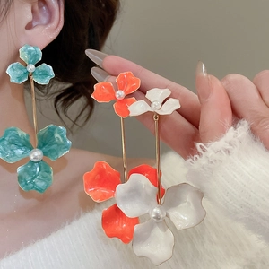 Close-up of floral drop earrings with pearl center in mint green and orange hues