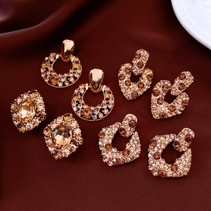 Dettaglio di orecchini vintage placcati oro con zirconi ambrati su seta rossa lussuosa