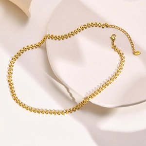Detailed macro view of a 18K gold wheat chain necklace on a minimalist white tray