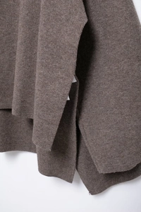 Close-up of brown knit fabric texture and drape of a loose scarf poncho coat