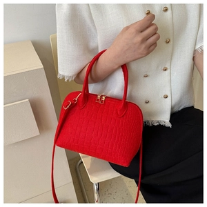 Detail of red crocodile pattern handbag with gold hardware shown on model