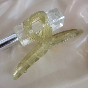 Translucent light green large claw clip with a glossy finish on soft beige silk background