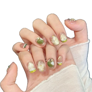 Handmade press-on nails featuring green apple charms and champagne gold glitter accents