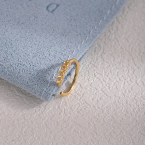 Macro shot of gold leaf nose ring with five white zircons on blue velvet bag