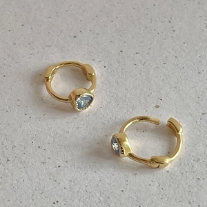 Detailed close-up of gold-plated hoop earrings featuring light blue heart-shaped stones