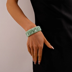Macro shot of light green geometric faceted resin elastic bracelet worn on a wrist