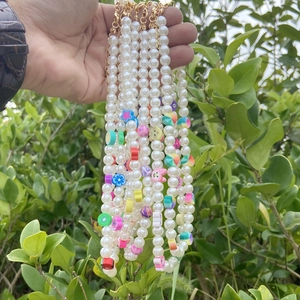 Detail of bohemian pearl necklaces with colorful fruit and flower beads held by hand