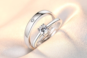 Detailed view of silver crown zircon couple rings on a soft beige fabric background