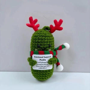 Detail of a handmade crochet emotional support cucumber with reindeer antlers and scarf