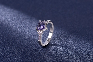 Macro shot of silver ring with heart-cut purple gemstone and pave-set violet accents