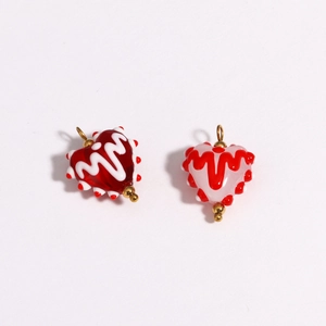 Detail of colorful heart-shaped glass charms with wave patterns and golden metal rings