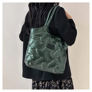 Detail einer grünen gesteppten Puffer-Tasche mit Fashion Bags Patch an einem Model