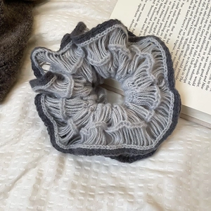Detail of knitted double-layered flower scrunchie with soft grey wool texture