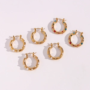 Detailed view of gold hoop earrings with pearls, clear zircons, and colorful gemstones