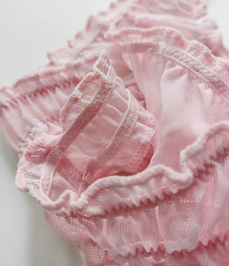 Macro detail of pink mesh thong showing ruffle edge trim and high-elastic fabric texture