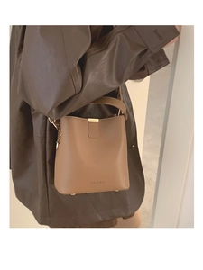 Detail of a brown leather bucket bag with top handle, gold hardware, and brand logo