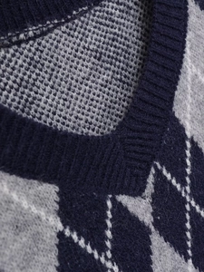 Detail of argyle knit pattern and ribbed V-neckline on a navy blue long sleeve sweater