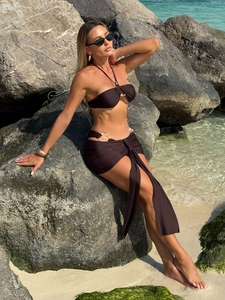 Detailed view of brown three-piece bikini with gold rings and matching beach sarong