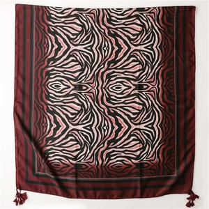 Close-up of zebra print silk scarf with deep red borders and elegant corner tassels