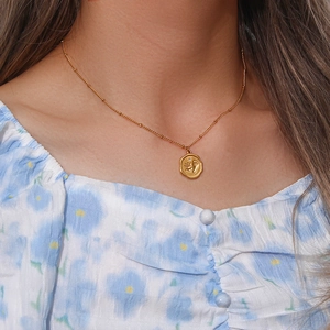 Détail du collier doré avec pendentif circulaire empreintes de bébé porté par un mannequin