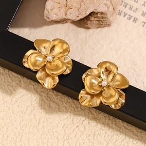 Close-up of vintage double-layer gold flower earrings with white pearl centers on dark frame