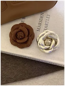 Detailed macro view of caramel felt and gold leather floral brooches on art book cover