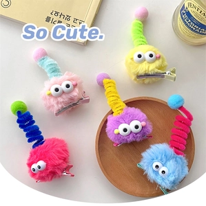 Close-up of cute plush monster hair clips with colorful fur and spiral antennae