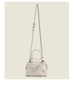 Détail du sac boston en similicuir crème avec un grand nœud en dentelle et bandoulière