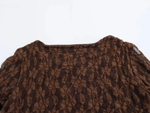 Detail shot of the crew neck and lace pattern on a dark brown bell sleeve long dress