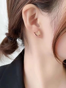 Close-up of elegant rose gold butterfly stud earrings with a brushed matte finish on ear