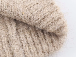 Primo piano del morbido tessuto a maglia jacquard beige con trama felpata e materiale caldo