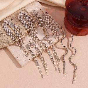 Détail de boucles d'oreilles à longs pompons avec zircons blancs sur support en pierre