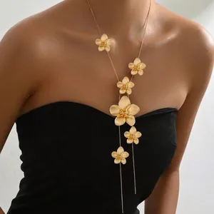 Detailed view of long gold floral Y-necklace with matte finish on a female model