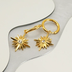 Detailed macro view of gold-plated hoop earrings with sparkling zircon starburst pendants