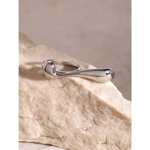 Irregular fluid silver ring displayed on natural raw stone with mirror-like finish