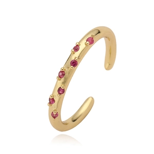 Detail of adjustable gold C-shaped ring set with seven sparkling red round gemstones