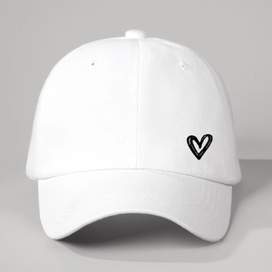 Détail de la broderie cœur sur une casquette blanche en coton à 6 panneaux avec œillets