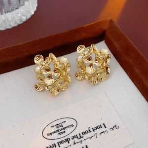 Macro shot of gold metal flower stud earrings with a hollow 3D design on a display card