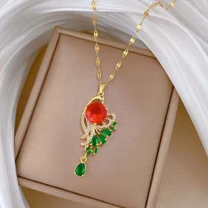 Detail of gold peacock pendant necklace with red round stone and green teardrop gems