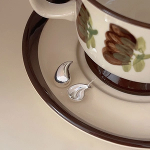 Polished 925 sterling silver teardrop earrings on a vintage floral ceramic saucer