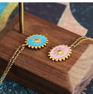Detail of oval enamel sun pendants in sky blue and pink on 18K gold titanium steel chains