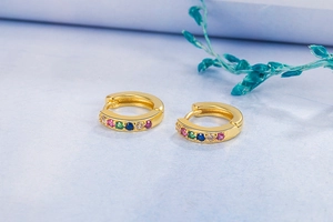 Close-up of small 14K gold hoop earrings featuring multi-color inlaid cubic zirconia stones