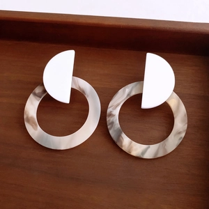 Detail view of round resin hoop earrings with marble texture on dark wooden tray