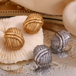 Detailed close-up of oval knot stud earrings with spiral texture in gold and silver