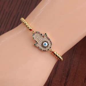 Détail du bracelet main de Fatma et œil protecteur en or avec cordon rouge et perles